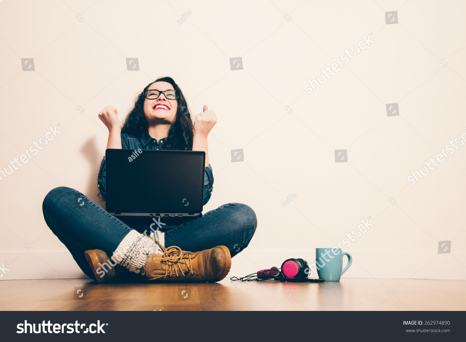 stock-photo-girl-sitting-on-the-floor-with-a-laptop-raising-his-arms-with-a-look-of-success-262974890